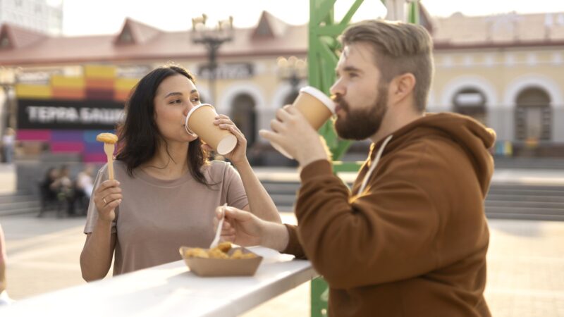 Tętniąca życiem warszawska ulica z restauracjami i ludźmi jedzącymi posiłki na zewnątrz.